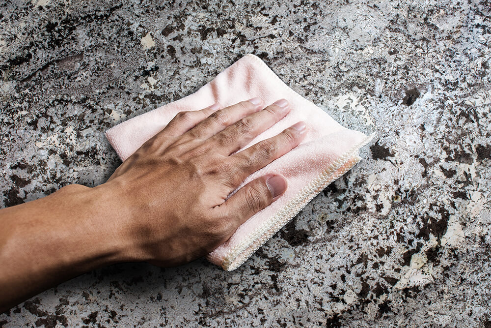 Persona limpiando con un trapo la encimera de piedra natural 