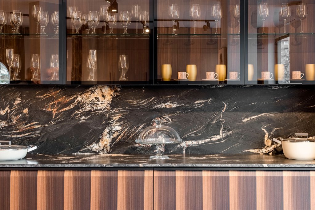 Encimera de cocina y salpicadero con cuarcita de color negro con vetas blancas y doradas, cuarcita San Giovanni. Muebles de cocina de madera.